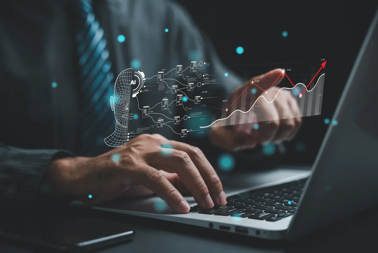 Professional working on a laptop with an AI facial-recognition wireframe and rising analytics graph projected above the keyboard