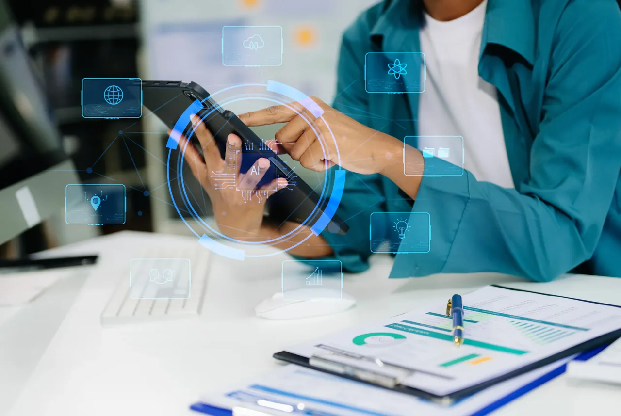 Professional in a teal jacket using a tablet surrounded by a connected network of floating technology and cloud icons